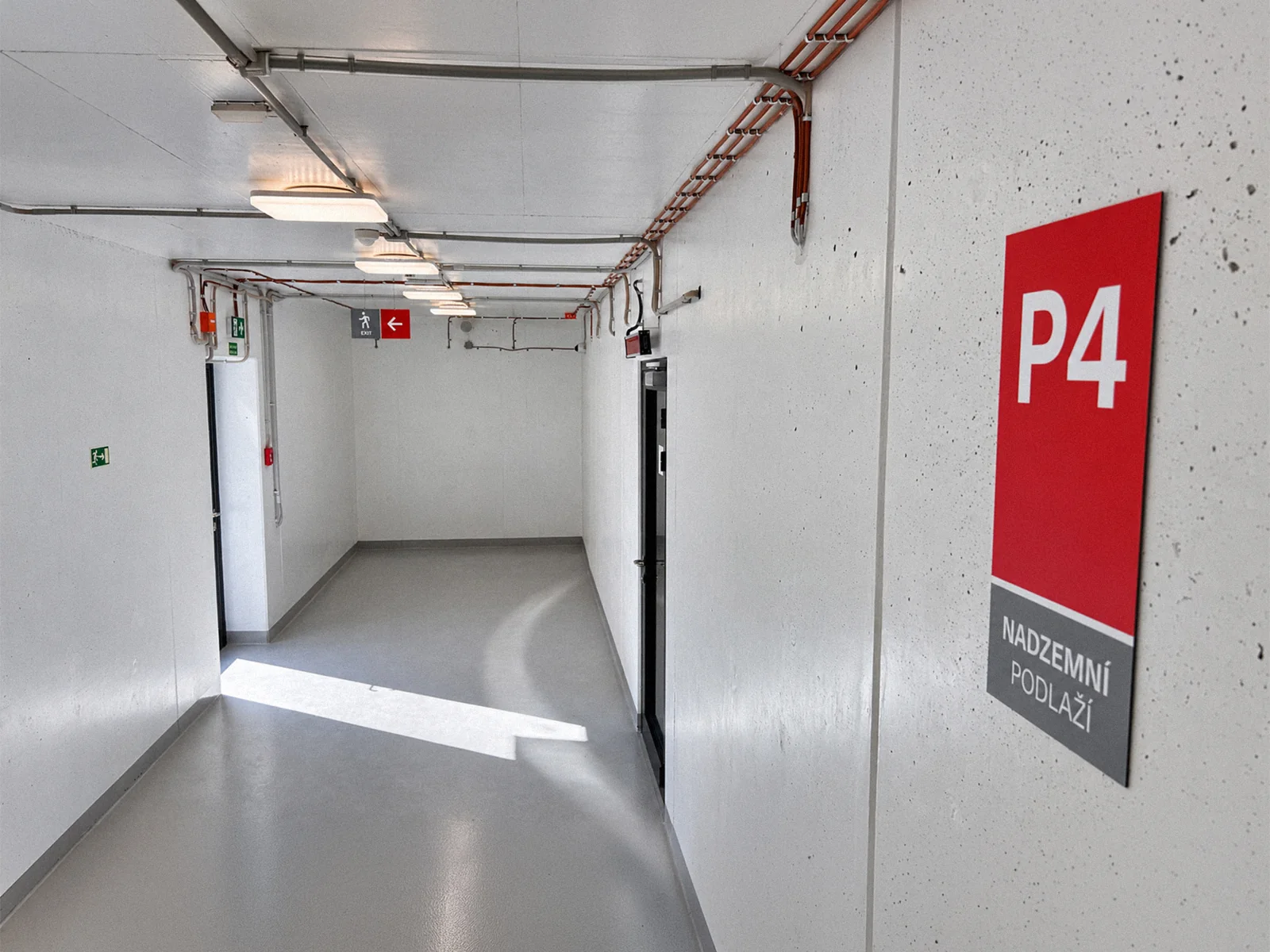 Červená cedule P4 na stěně garáže Dědina vedle bílé směrové šipky